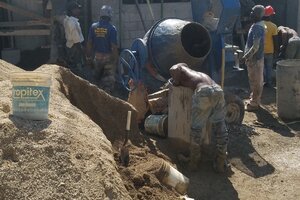 Workers mixing concrete and taking it up to the second floor.
