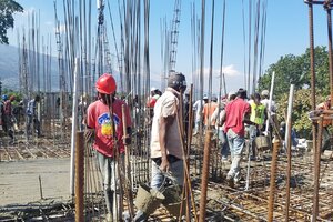 Workers taking concrete across the second floor - bucket by bucket.