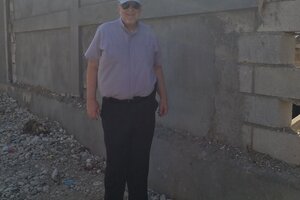 Fr Frank in front of the wall around the Norwich Outreach Center .