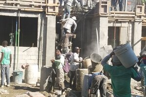 Workers mixing concrete and taking it up to the second floor.